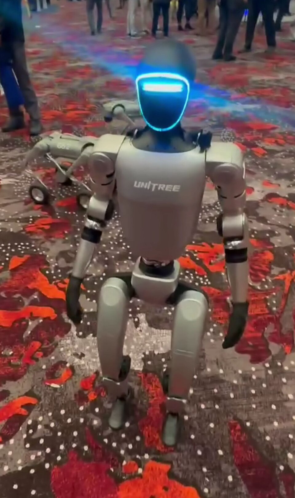 A Unitree G1 humanoid robot walking at a trade show